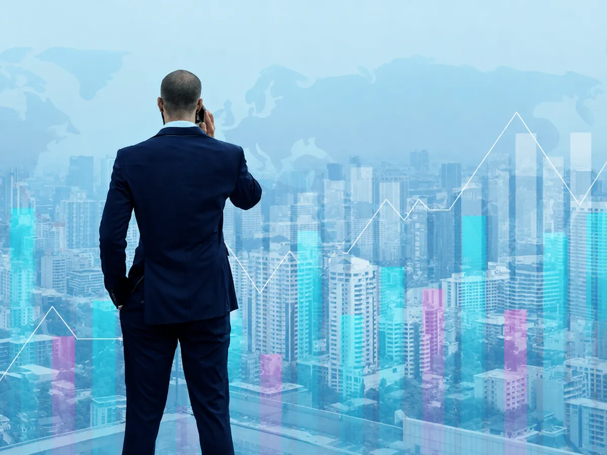 A finance leader looking out over a city skyline overlaid with growth charts.
